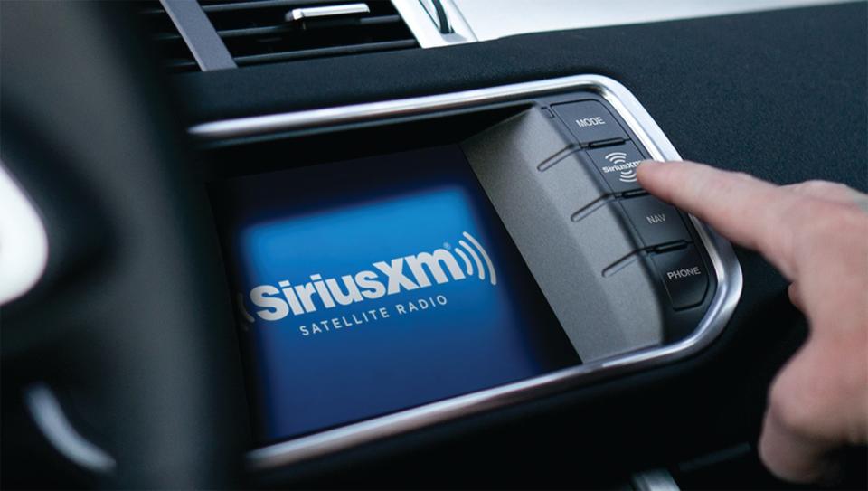 Một người đang nhấn nút radio vệ tinh Sirius XM trên bảng điều khiển trong xe hơi. 