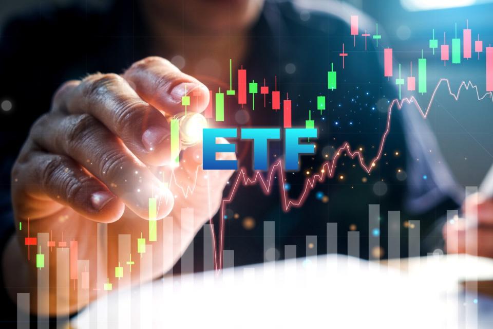 Một bàn tay chỉ vào biểu đồ chứng khoán với "ETF" hiện ở phía trước biểu đồ.