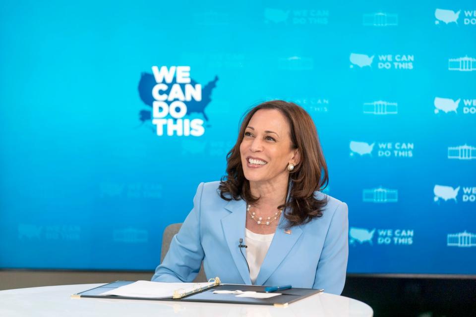 Phó Tổng thống Kamala Harris ngồi sau bàn làm việc và mỉm cười.